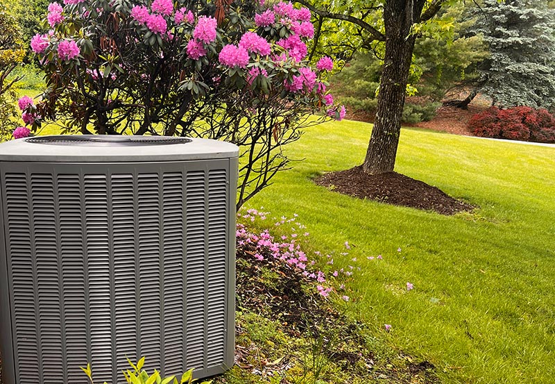 Heat pump outdoor unit sitting outside in backyard.